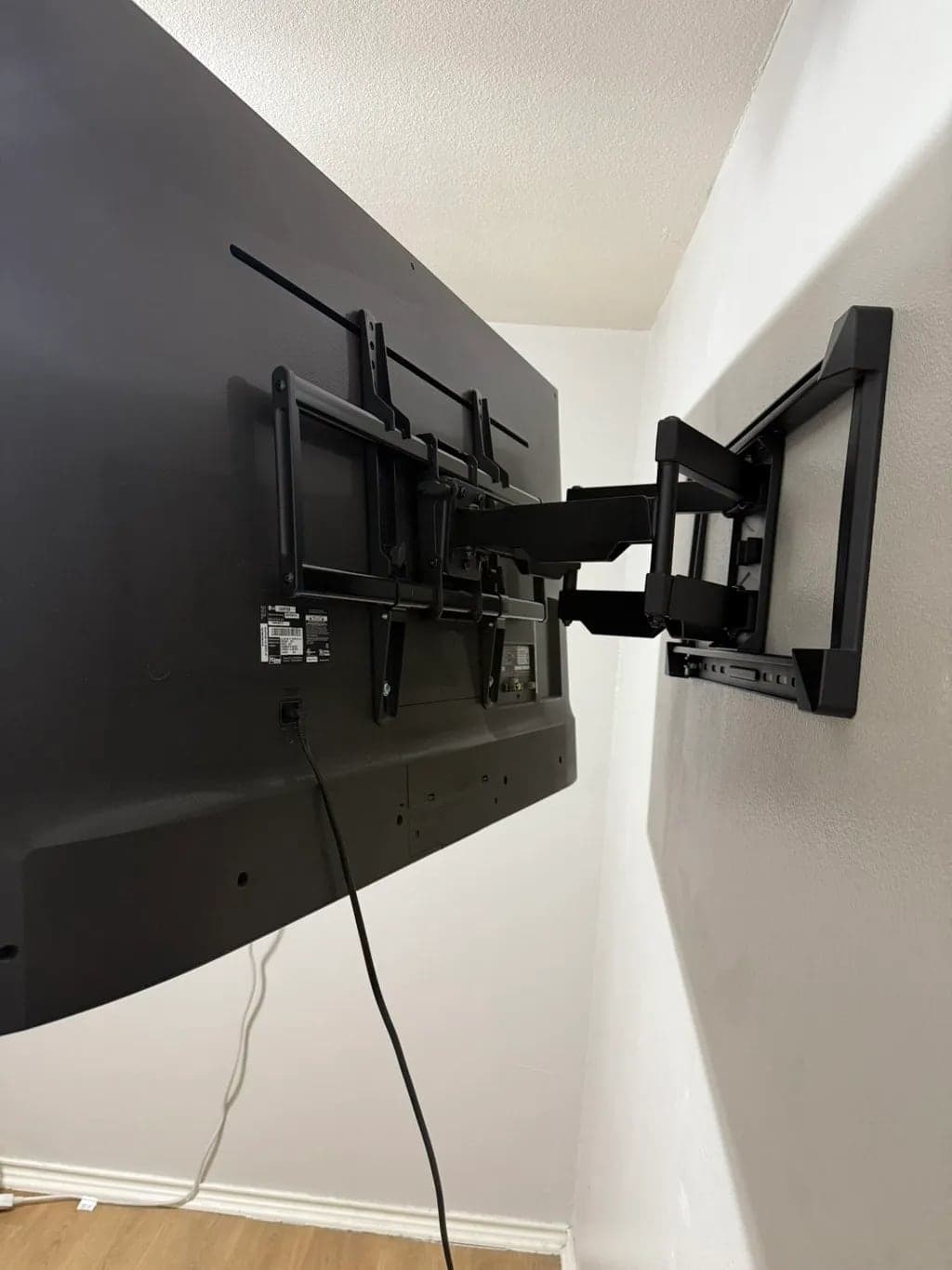 Back of a TV on a full-motion wall mount extended out from a drywall wall
